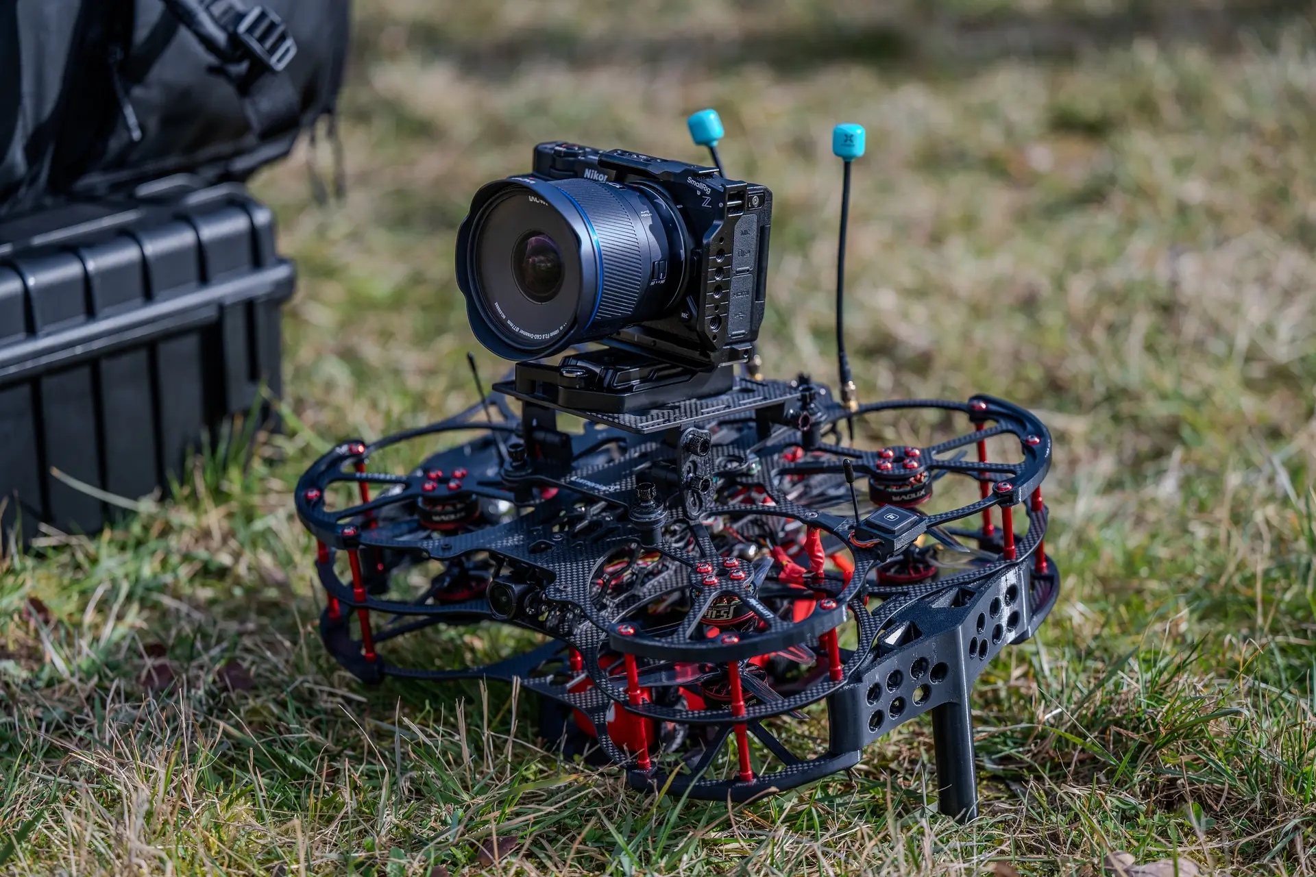 FPV-Drohne mit Kinokamera steht startbereit auf einer Wiese