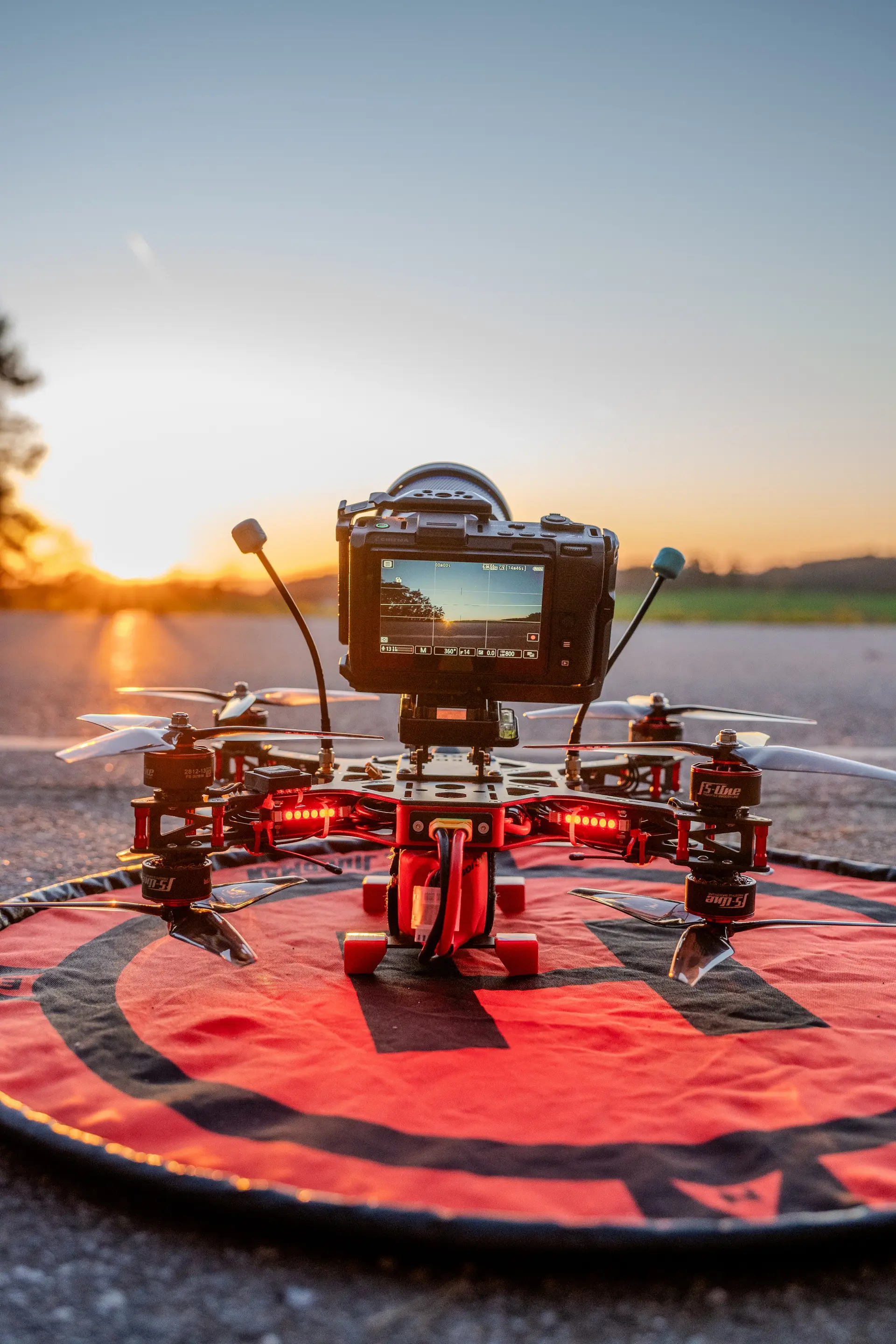 FPV-Drohne mit Actionkamera auf einem Landeplatz im Sonnenuntergang