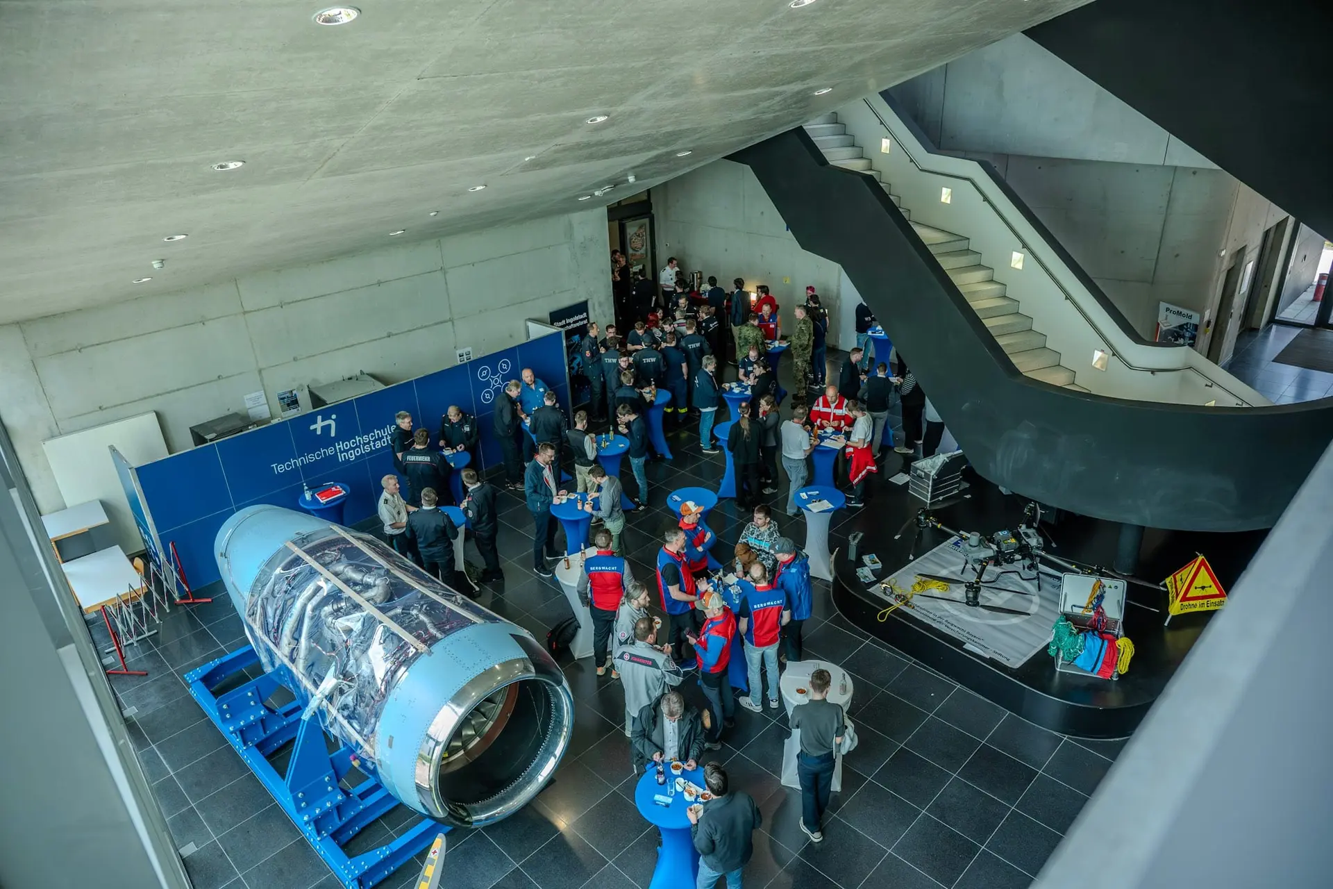 Veranstaltung in einem Foyer mit Ausstellungsstücken und vielen Gästen, von oben fotografiert