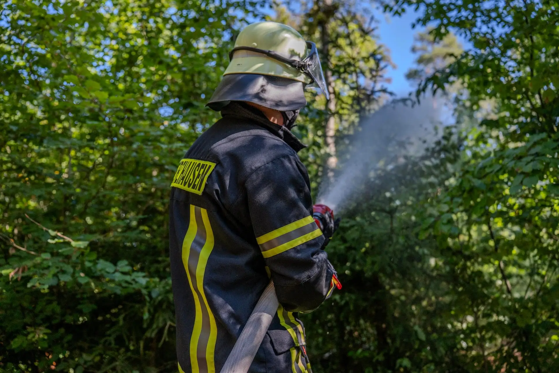 Feuerwehrmann löscht mit dem Strahlrohr im Wald