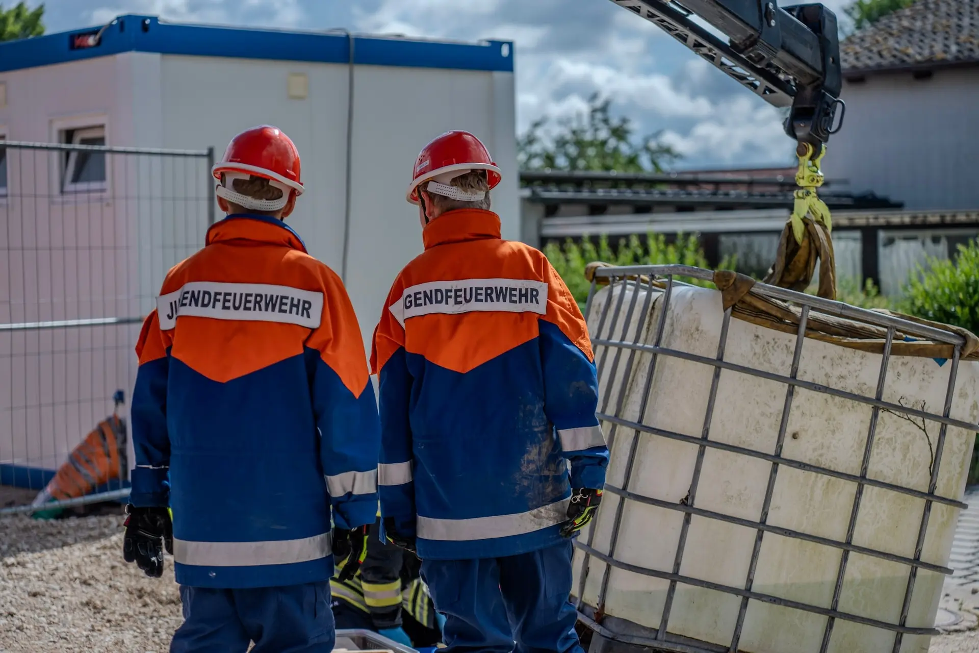 Zwei Mitglieder der Jugendfeuerwehr bei einer Übung, von hinten fotografiert