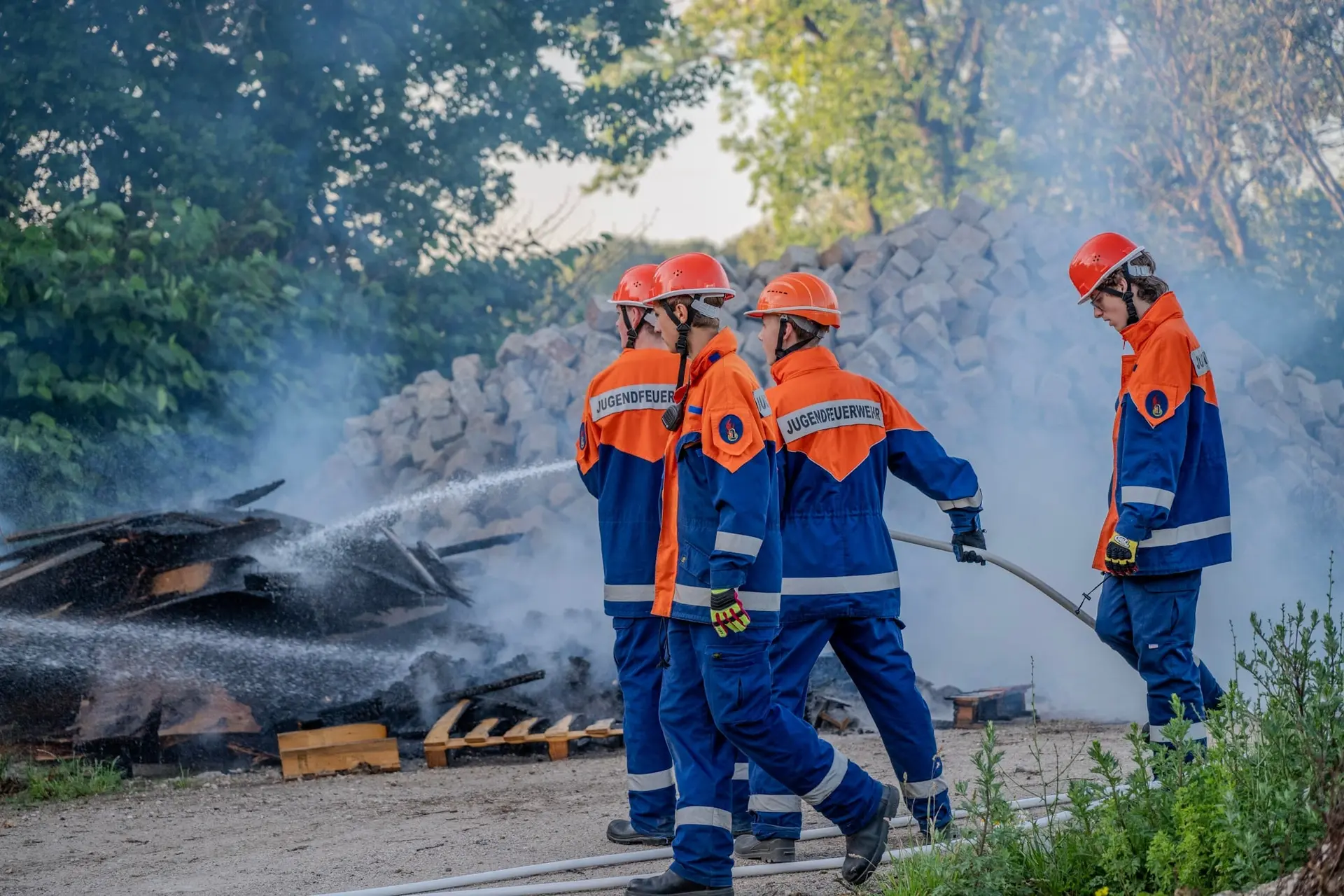 Jugendfeuerwehr löscht einen brennenden Holzstapel