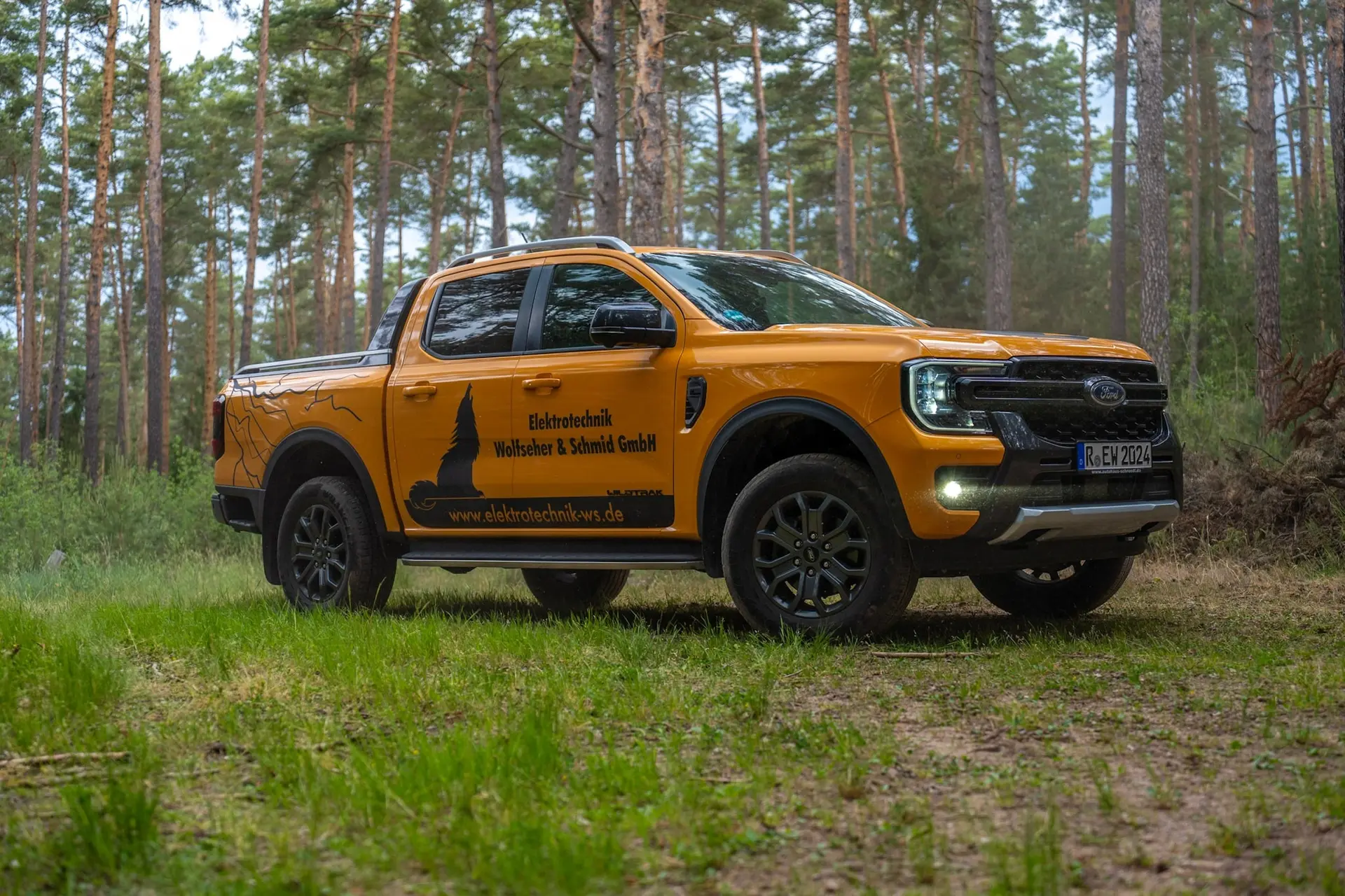 Orangefarbener Pick-up der Elektrotechnik Wolfseher & Schmid GmbH im Kiefernwald