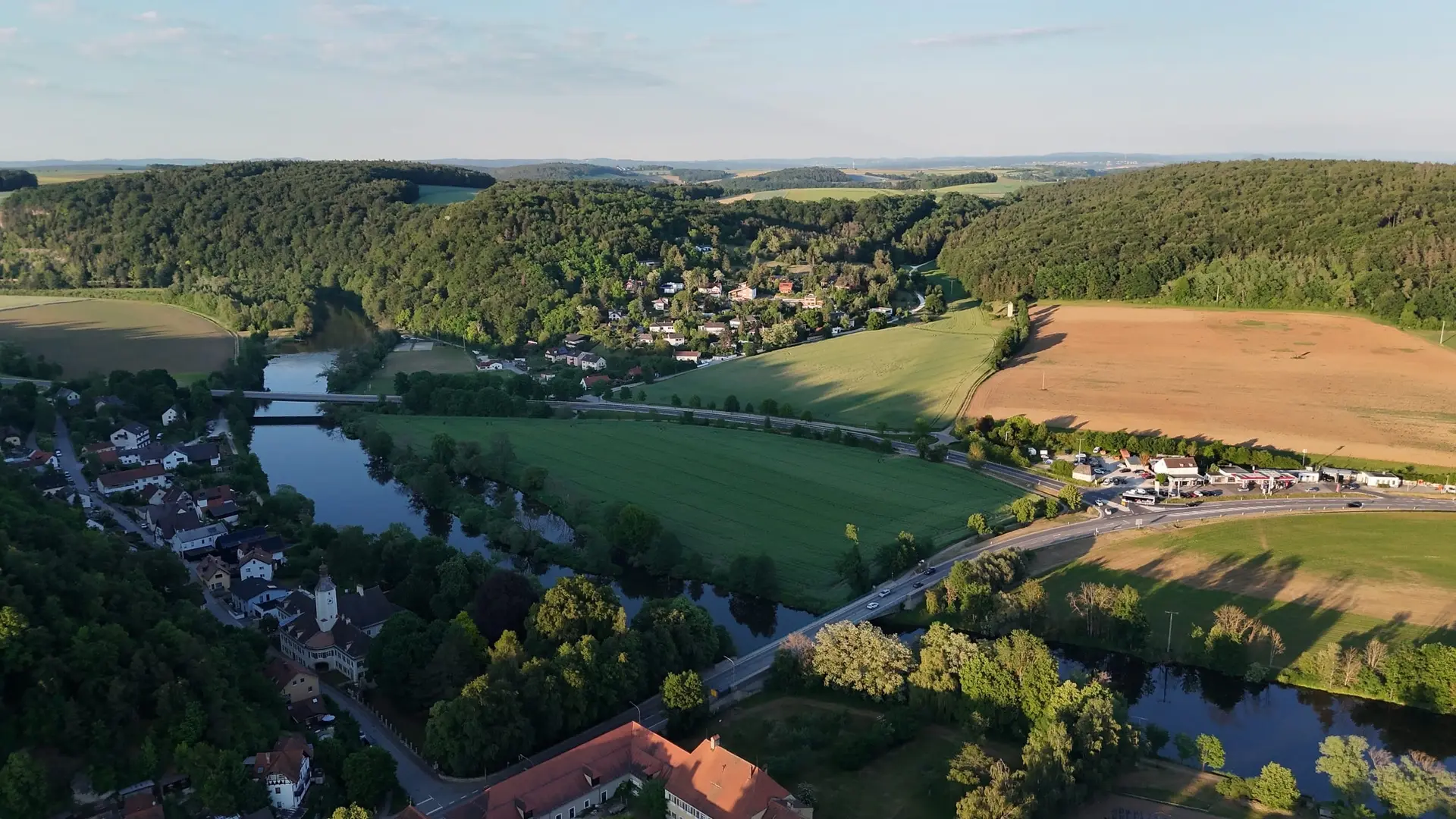 Flusstal mit Ortschaft im Abendlicht