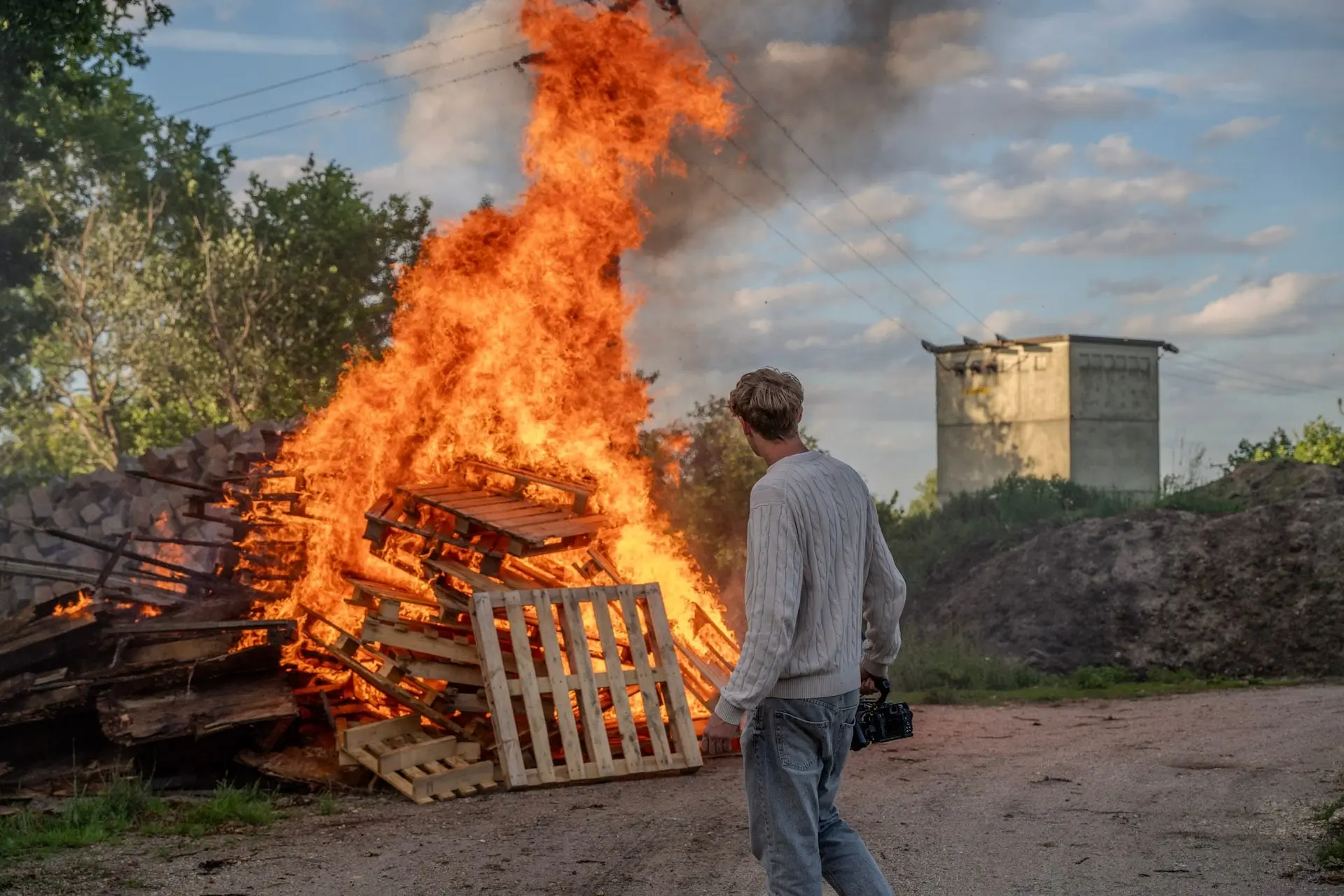 Kameramann geht mit seiner Kamera auf ein großes Feuer zu