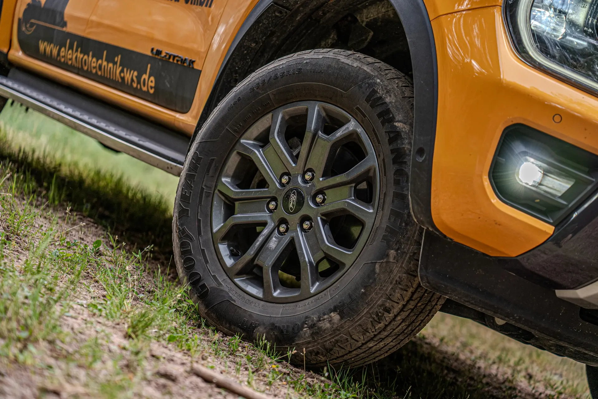 Vorderrad eines orangefarbenen Pick-ups mit Firmenbeschriftung