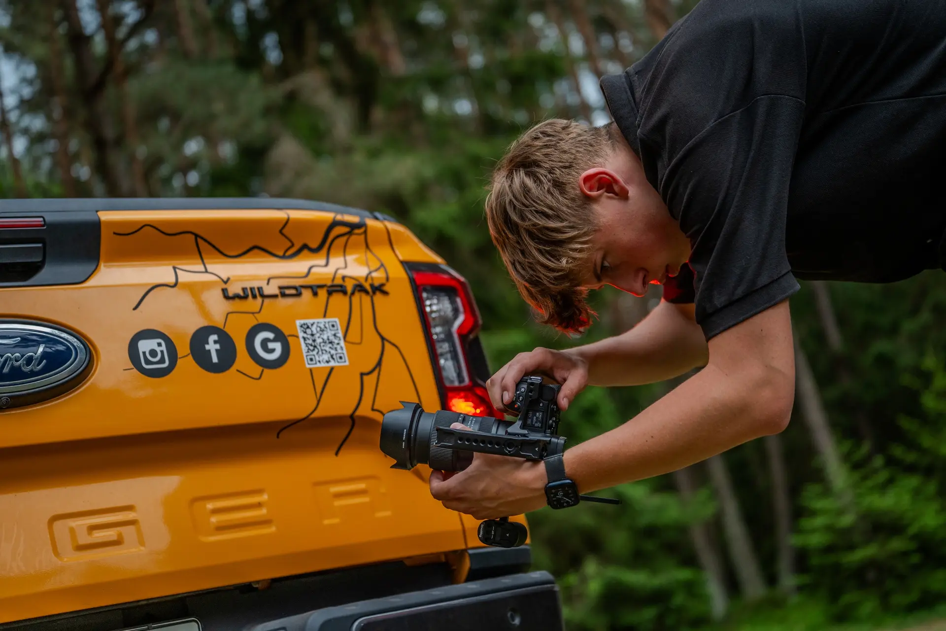 Fotograf fotografiert das Heck eines Pick-ups mit Social-Media-Symbolen und QR-Code